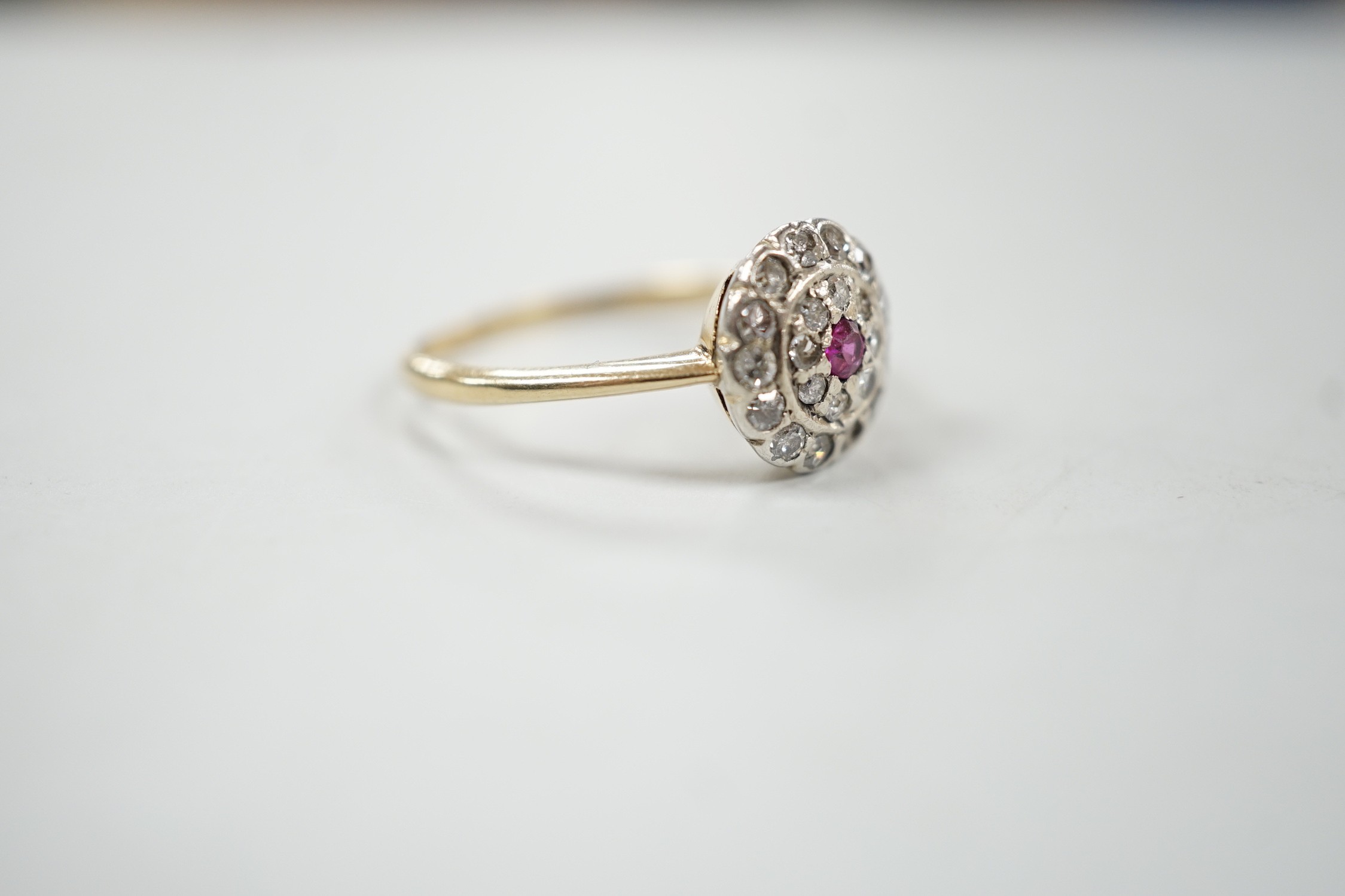 An early to mid 20th century, yellow metal ruby and diamond set target cluster ring, size P, gross weight 2.8 grams.